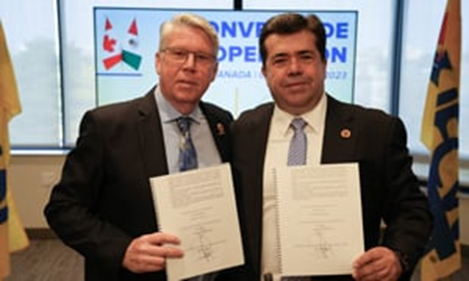 A couple of men holding papersDescription automatically generated